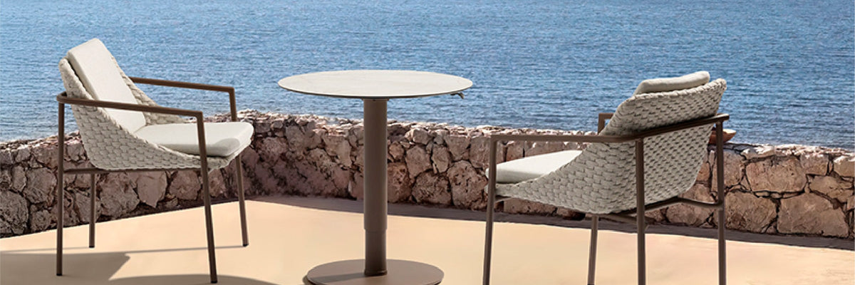 Two woven-rope Enjoy outdoor dining chairs at a round bistro table on a seaside terrace