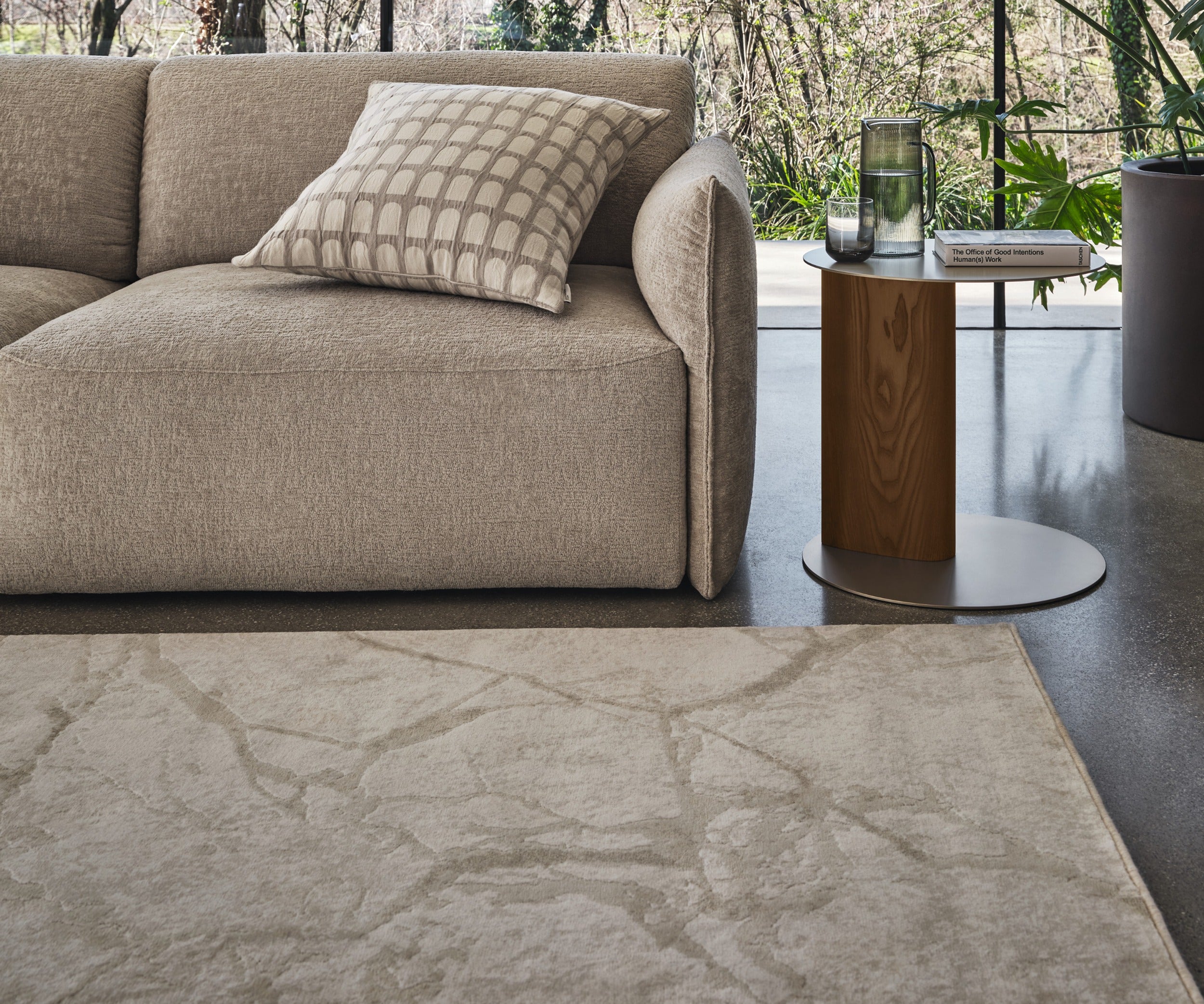 Cave rug by Calligaris in front of a beige fabric sofa and a wood side table