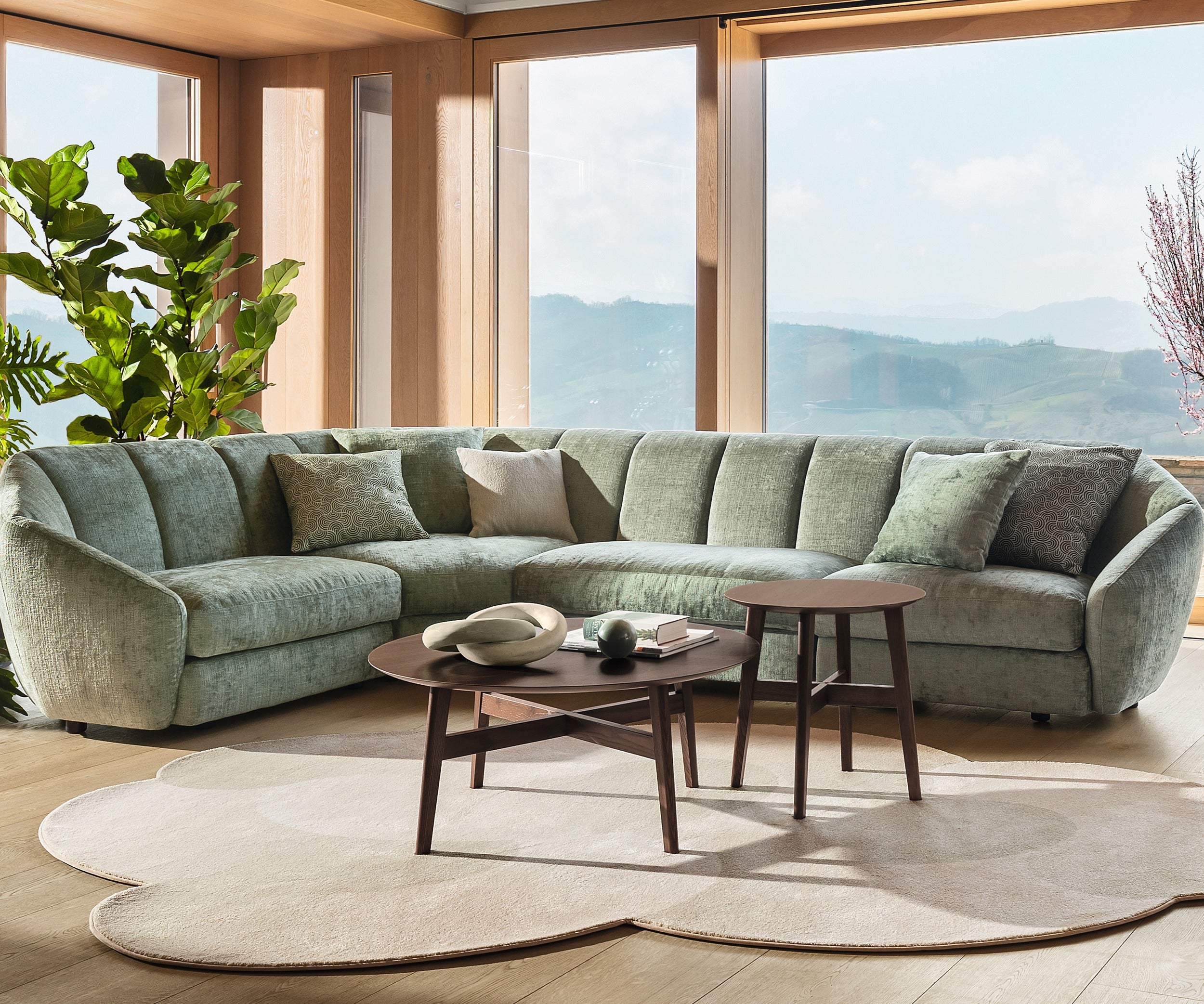 Curved rug by Calligaris under round coffee tables in front of a green sectional sofa