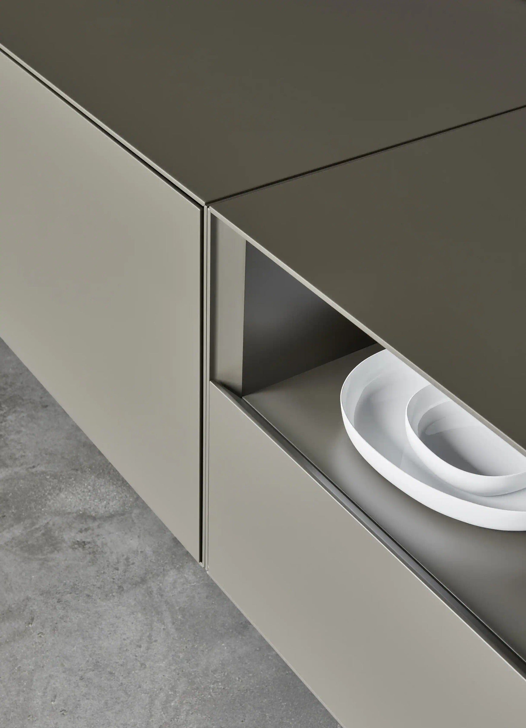 Domino Composition 9298 detail: handle-free Domino base front with inclined edge and open compartment in matt taupe