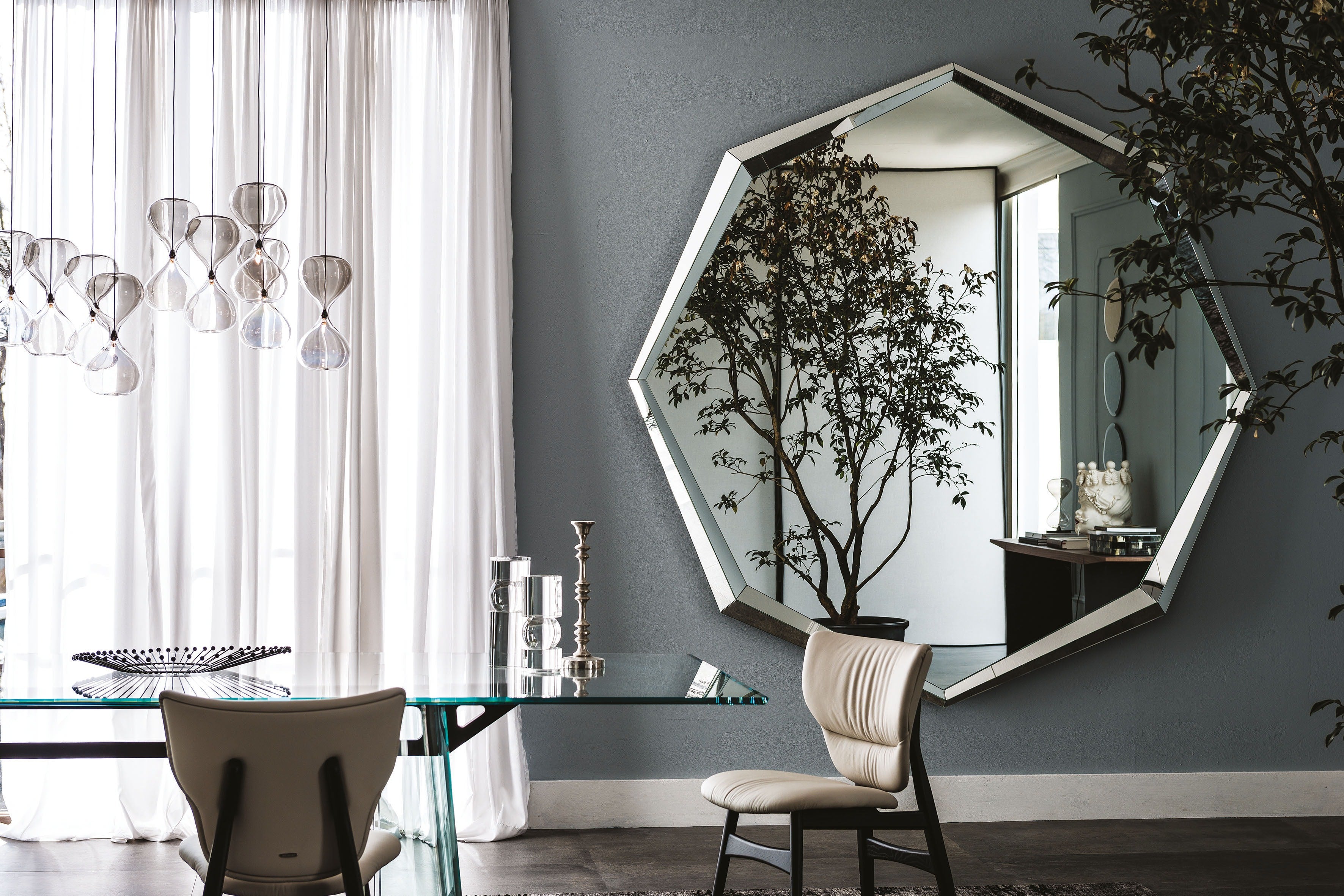 Emerald Magnum mirror: dining room: Emerald Magnum on a blue-grey wall beside a glass table