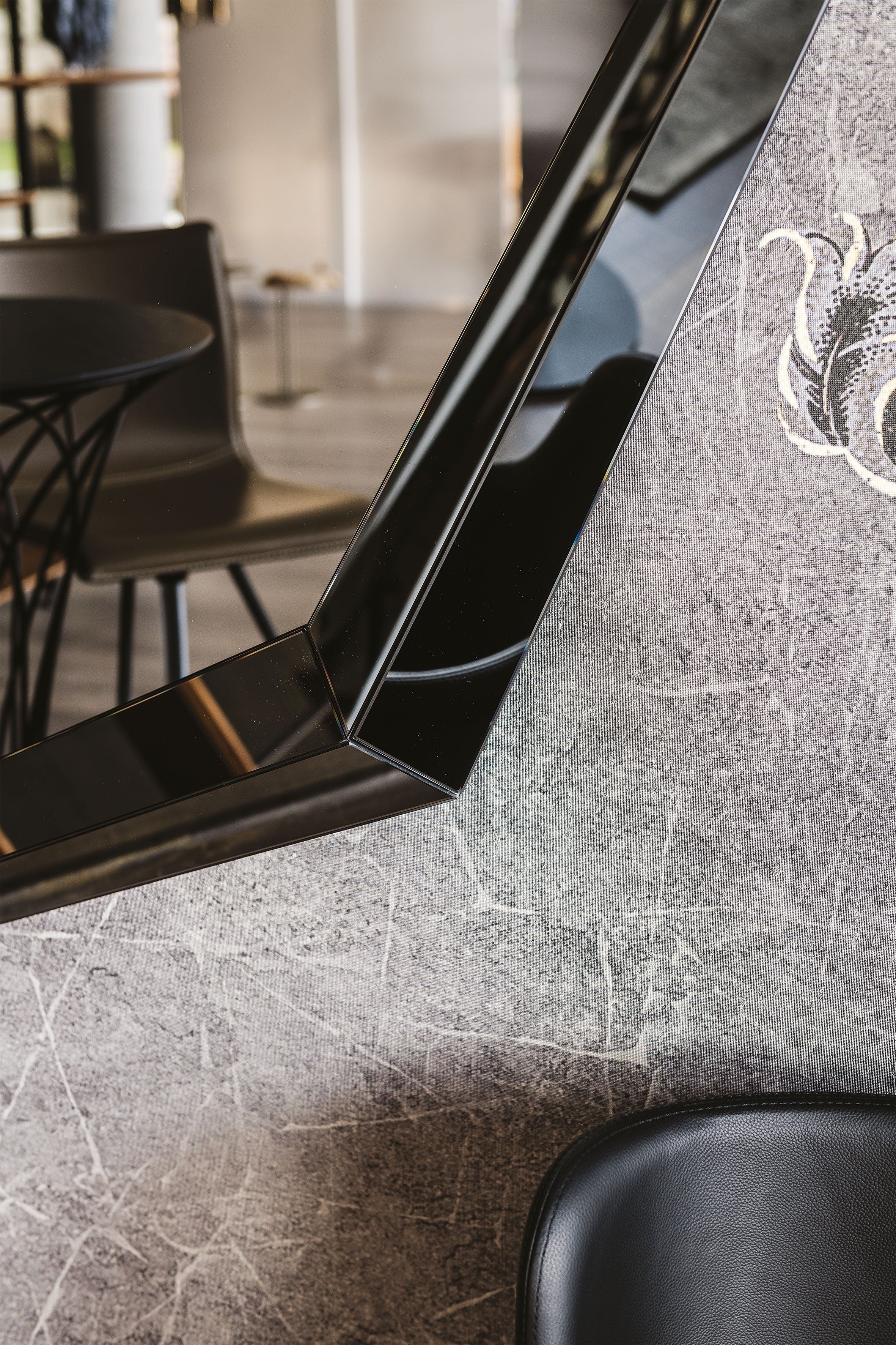 Emerald Magnum mirror: close-up of the angled mirrored frame edge against a grey plaster wall