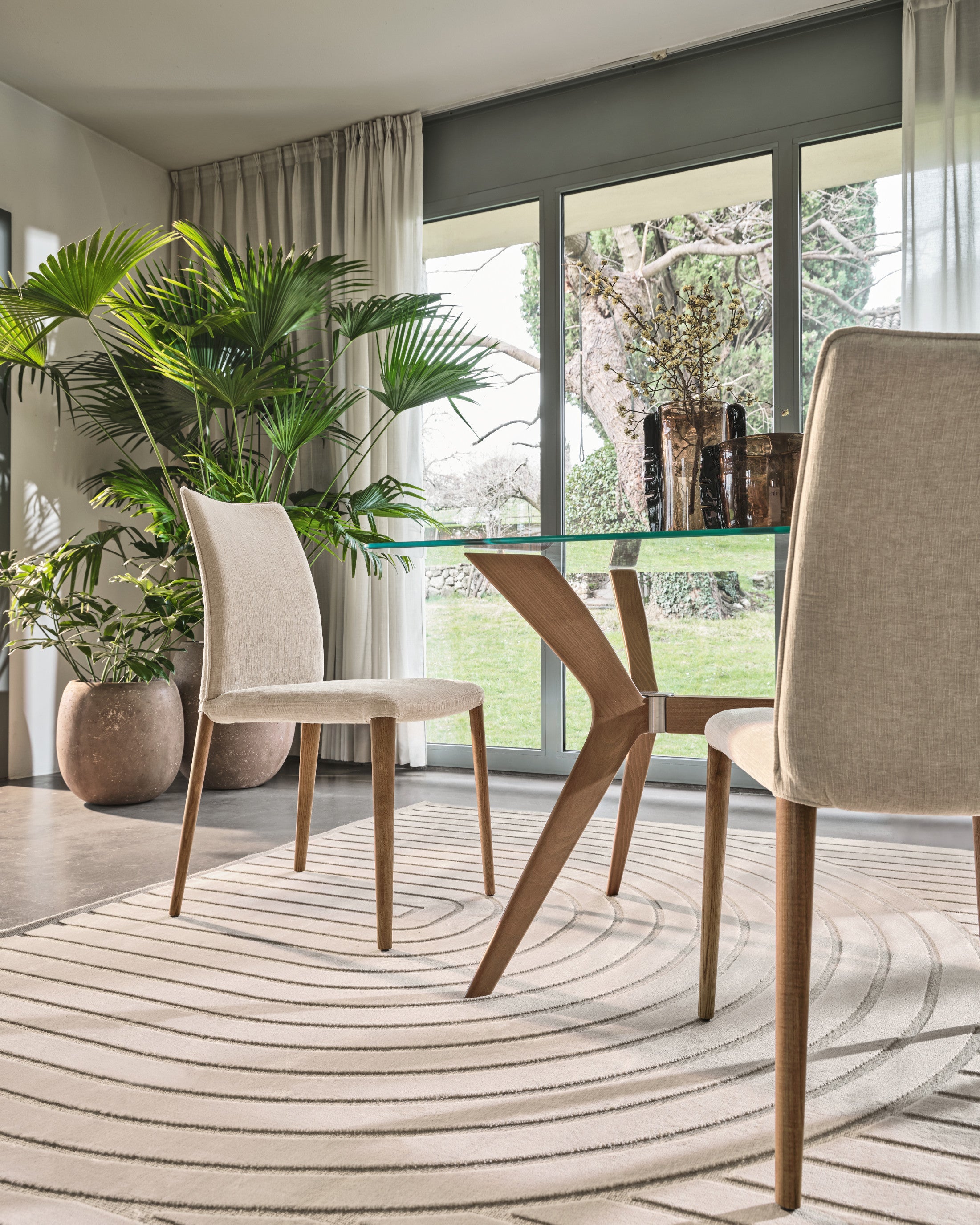 Mirage rug by Calligaris in Ecru/Beige under a glass dining table with upholstered side chairs