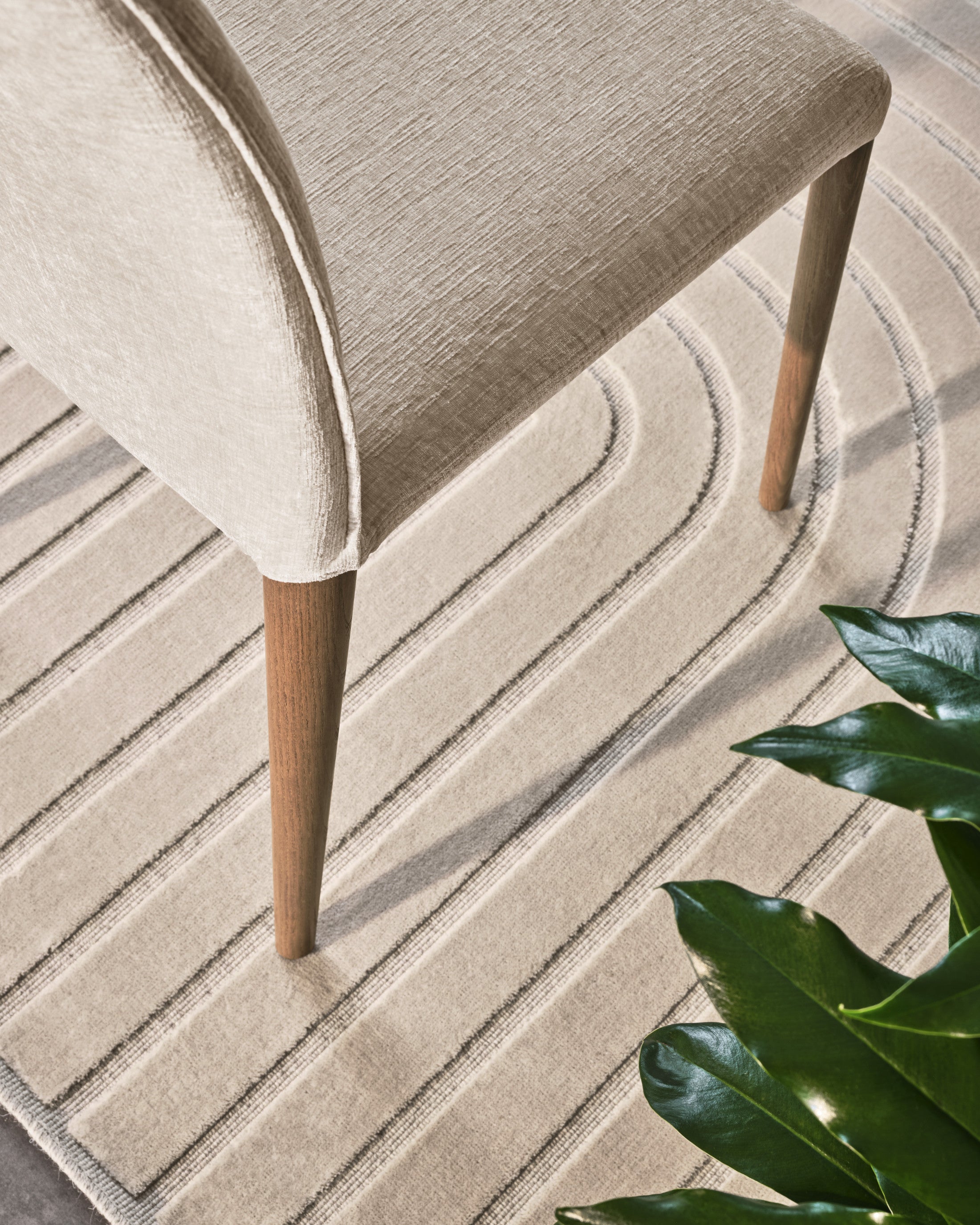 Close-up of the Mirage rug by Calligaris in Ecru/Beige showing its line pattern under a dining chair leg
