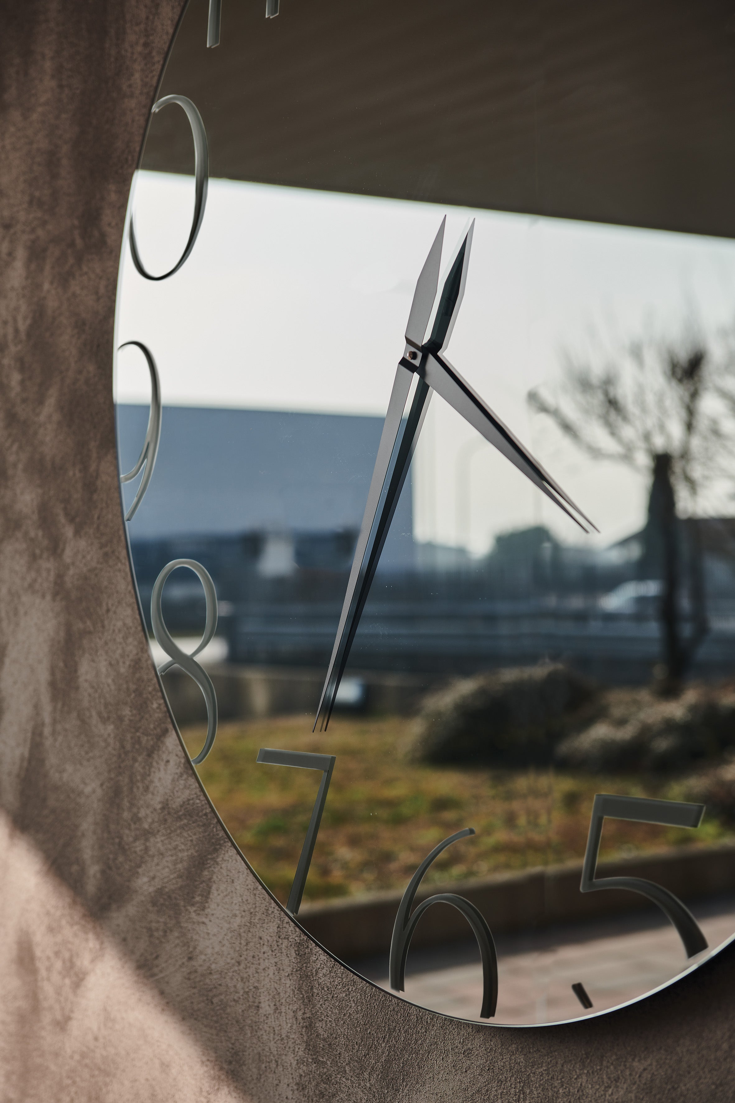 Moment mirror: angled close-up of the hands and printed numerals 5-9, with an outdoor scene reflected in the glass