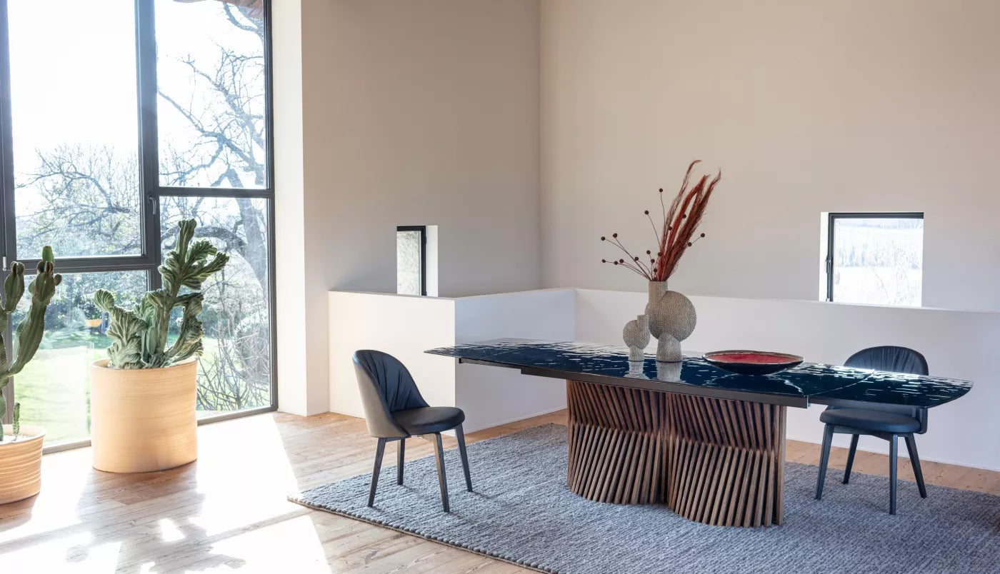 Nest A Double extendable dining table by Natisa in a bright dining room with black dining chairs