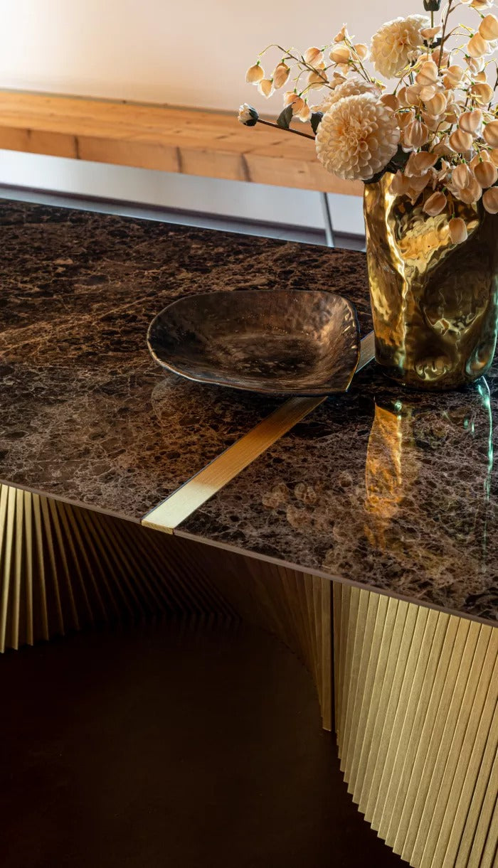 Close-up of the Orbit gold-finish base strips beneath a dark marble-look top